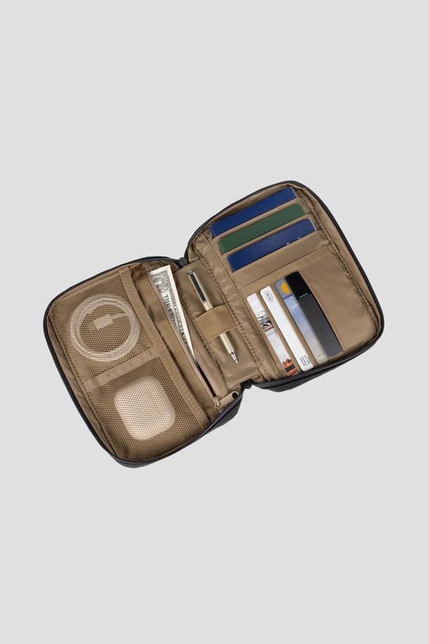 블랙 색상의 Staple Passport Pouch는 여행 및 일상에서 활용하기 좋은 스몰 사이즈의 여권지갑입니다. 나일론 소재로 제작되어 생활 방수가 가능하며, 여권 3개와 카드 4장을 수납할 수 있는 넉넉한 공간을 제공합니다. 탈부착 가능한 어깨 스트랩과 후면 카드 슬롯, 메쉬 포켓, 펜 포켓 등의 디테일이 더해진 사각 형태의 지퍼형 여권지갑입니다.
