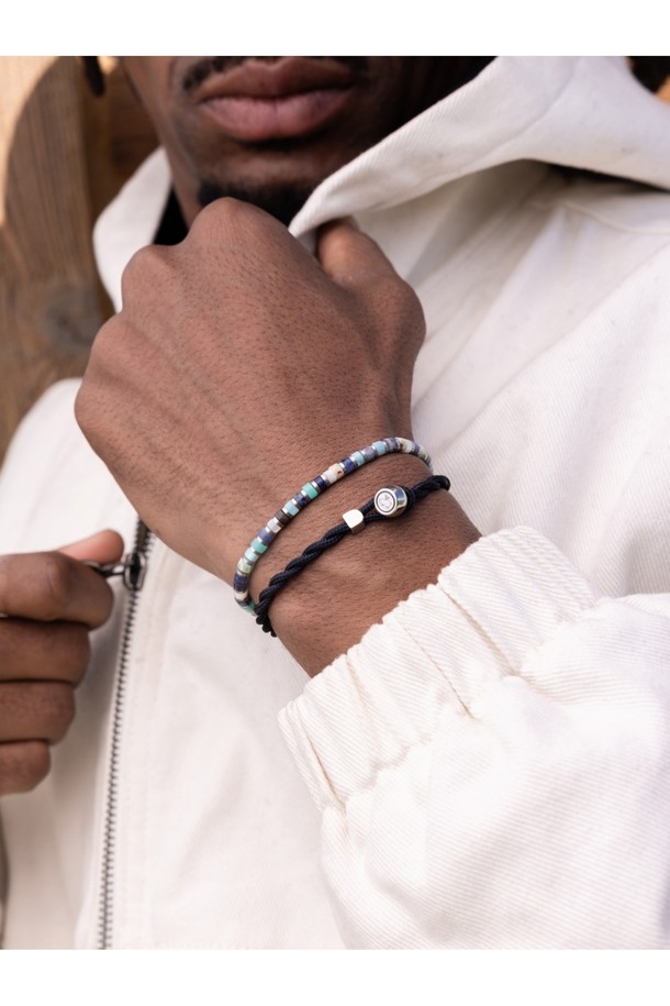 브론타이드 4 팔찌 - '후지'와 실버 컬러의 조화가 돋보이는 브론타이드 4 팔찌입니다. 공용으로 착용 가능하며, 스테인리스 스틸과 마린 로프 소재를 사용하여 내구성과 방수 기능을 갖췄습니다. 4mm 두께의 브레이드 패턴, 번개 디자인 모티브, 수작업 매듭 디테일이 특징이며, 슬라이더로 사이즈 조절이 가능합니다. 미니멀하고 캐주얼한 스타일로 일상, 해양스포츠, 휴가, 여행 등 다양한 TPO에 매치하기 좋습니다. 다른 팔찌와 레이어드하여 개성 있는 스타일을 연출할 수도 있습니다.
