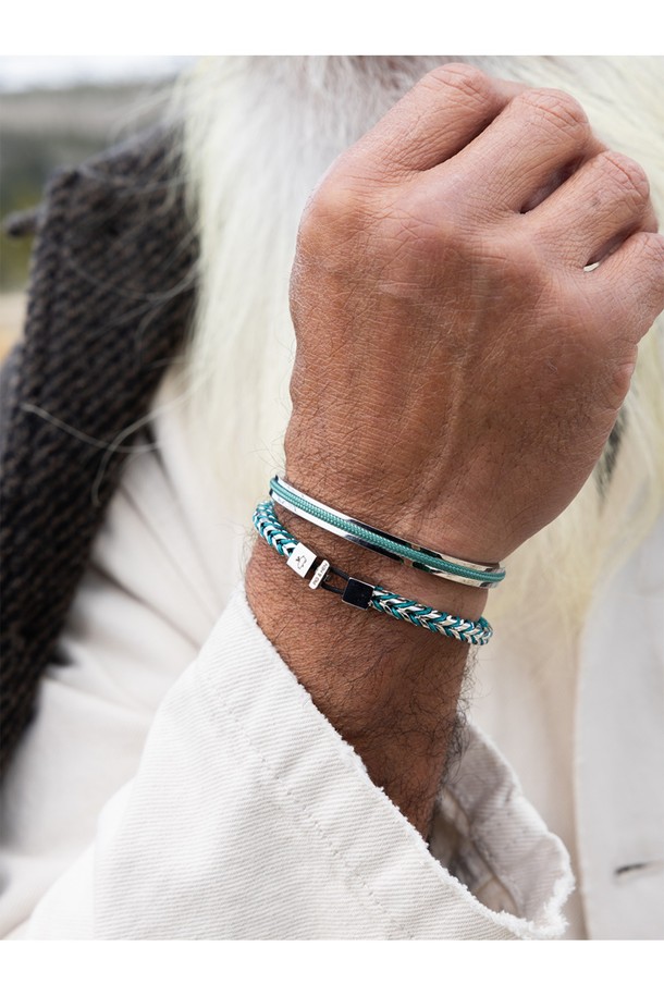 "나바크 6" 팔찌는 파티나그린 색상과 실버 색상의 조화가 돋보이는 공용 팔찌입니다. 316L 의료용 스테인리스 스틸과 1.8mm 고강도 마린로프를 사용하여 제작되어 일상생활은 물론 마린 스포츠 활동에도 적합합니다. 미니멀하고 캐주얼한 스타일로, 여행룩에 포인트 아이템으로 활용하기 좋습니다. 레이저 각인으로 디자인 포인트를 더했으며, 방수, 내식성, 내구성이 뛰어나 변색 없이 오래도록 착용할 수 있습니다. 100% 수작업으로 꼼꼼하게 제작되었으며, 비노출 이음새 마감과 소금물 저항성을 갖춰 섬세함과 실용성을 모두 놓치지 않았습니다.
