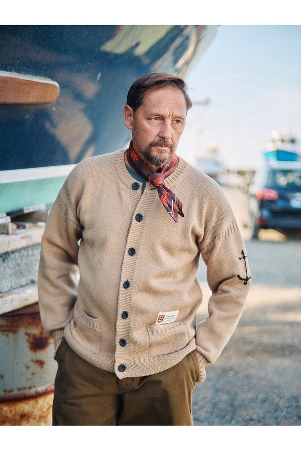 네이비 컬러의 헤비코튼 피셔맨 헤리티지 가디건입니다. 가을과 겨울, 일상 속에서 클래식하고 베이직한 스타일을 연출하기 좋습니다. 두꺼운 두께감의 면 소재로 제작되어 보온성을 높였으며, 단단한 촉감이 특징입니다. T자 형태의 헤리티지 패턴과 파도와 빗줄기를 형상화한 케이블 및 다이아몬드 무늬 짜임, 왼쪽 소매의 앵커 포인트가 돋보입니다. 핑거홀과 밑단 절개 디테일, 라운드넥, 레귤러핏, 긴소매, 버튼 여밈 방식으로 디자인되었습니다.
