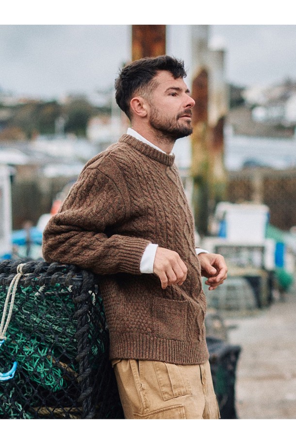 셔틀랜드울 아란 포켓 스웨터 - 모스 브라운은 클래식과 베이직 스타일을 추구하는 남성을 위한 겨울, 가을용 상의입니다. 두꺼운 두께감과 뻣뻣한 촉감, 보온 및 방풍 기능을 갖춘 이 스웨터는 일상과 출근룩, 모임룩에 적합합니다. 17세기 전통 편직 기법을 보존하여 제작되었으며, 전통적인 아란 니트 패턴과 포켓 디테일이 특징입니다. 링킹 기법으로 마감되었고, 아시아 체형에 맞는 사이즈로 제작되어 편안한 착용감을 선사합니다. 라운드넥, 긴소매, 레귤러핏의 레귤러 기장으로 디자인되었습니다.
