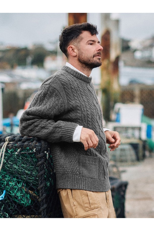 **[상품명: 셔틀랜드울 아란 포켓 스웨터 - 그레이]**

부드러운 촉감의 셔틀랜드울 소재로 제작된 아란 패턴의 포켓 스웨터입니다. 클래식한 무드의 이 스웨터는 가을과 겨울에 따뜻하게 착용하기 좋으며, 두꺼운 두께감으로 포근함을 더합니다. 긴 소매와 라운드넥 디자인으로 어떤 스타일에도 잘 어울리며, 입체적인 질감과 벌키한 짜임이 특징입니다. 전통적인 피셔맨 스타일을 현대적으로 재해석하여, 일상에서 편안하게 즐길 수 있는 아이템입니다. 그레이, 모스, 브라운, 라이트 그레이 등 다양한 컬러로 만나보세요.
