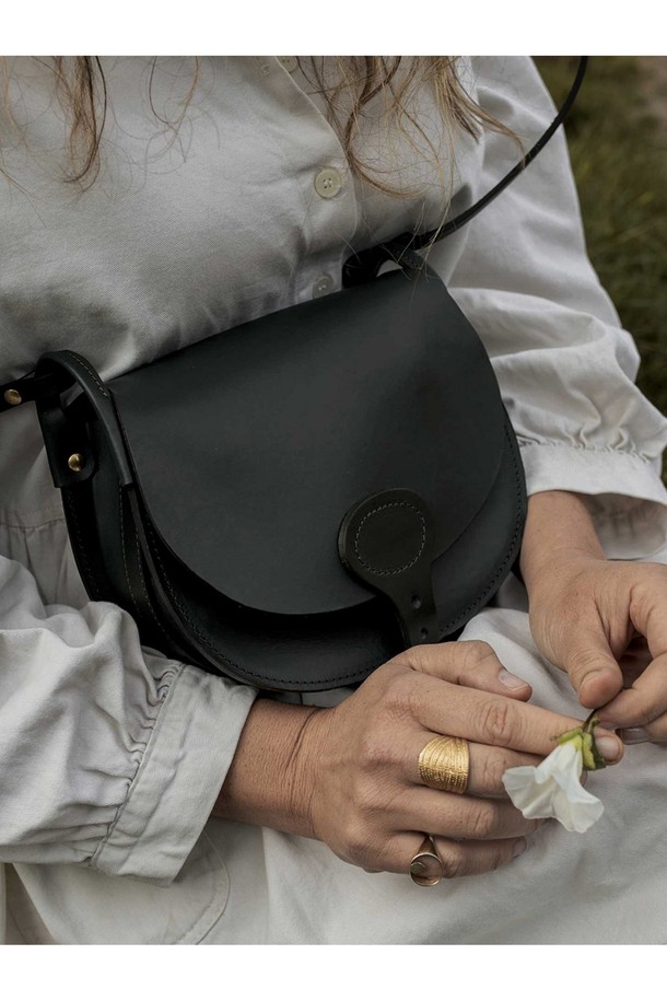 다이앤 새들백 M - 누아르 블랙은 출근룩, 비즈니스 캐주얼, 모임룩에 모두 잘 어울리는 남성용 새들백입니다. 클래식, 미니멀, 시크 스타일을 추구하는 남성에게 적합하며, 부드러운 소가죽 소재로 제작되어 고급스러운 질감을 선사합니다. 가방은 무지 패턴의 블랙 컬러에 버클 장식으로 포인트를 더했으며, 반원 형태의 디자인과 마그네틱형 잠금 방식으로 실용성을 높였습니다. 내부에는 분리 수납이 가능한 구조와 YKK 지퍼를 적용하여 수납력을 강화했으며, 식물성 태닝 가죽, 유기농 면 내부, 황동 하드웨어를 사용하여 섬세하게 제작되었습니다.
