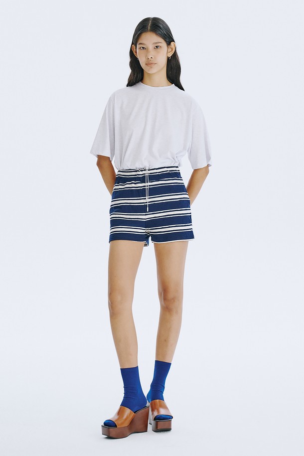 네이비 컬러의 스트라이프 자카드 니트 쇼츠는 여름철 데일리 및 홈웨어룩에 활용하기 좋은 여성 숏팬츠입니다. 면 소재로 제작되어 얇고 시원하며, 허리 전체 밴딩 처리로 편안한 착용감을 선사합니다. 클래식하면서도 캐주얼한 무드를 동시에 연출하며, 독특한 스트라이프 패턴과 레귤러핏 디자인으로 다리 라인을 더욱 길고 슬림하게 보이게 합니다.

