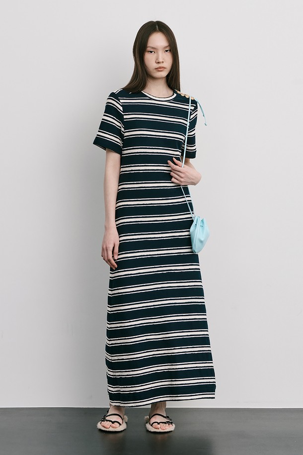 네이비 컬러의 스트라이프 자카드 니트 원피스입니다. 부드러운 Cotton 100% 소재로 제작되었으며, 봄, 여름 시즌에 어울리는 얇은 두께감과 A라인 핏, 라운드넥 디자인이 특징입니다. 허리를 잘록하게 잡아주는 실루엣과 밑단으로 갈수록 퍼지는 스커트 라인, 옆 네크 라인의 로고 금속 단추 디테일로 미니멀하면서도 클래식한 무드를 연출합니다.
