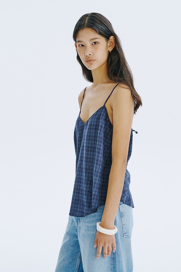 네이비 컬러의 체크 패턴이 돋보이는 민소매 탑입니다. 부드러운 면 80%와 레이온 20% 혼방 소재로 제작되어 시원하고 편안한 착용감을 선사하며, 브이넥 디자인에 아일렛 디테일과 끈 조절이 가능한 특징이 있습니다. 여름철 일상룩에 클래식하면서도 미니멀한 포인트를 더해줄 레귤러핏 상의입니다.
