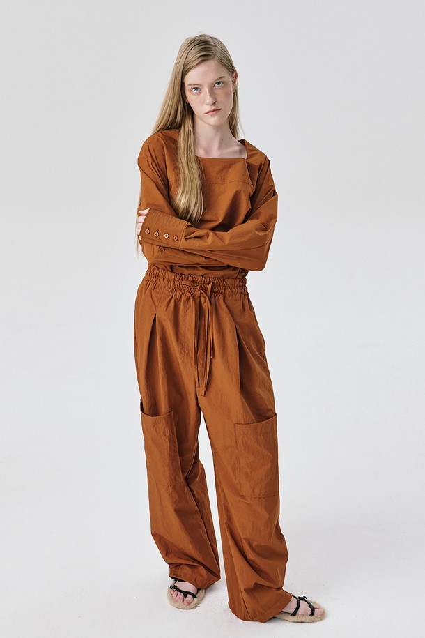 Yoke Top_브릭은 여성스러운 무드를 연출하는 블라우스입니다. 얇은 두께감의 나일론 소재로 제작되어 가을과 겨울에 적합하며 드라이한 촉감으로 편안한 착용감을 선사합니다. 톤 다운된 브릭 컬러와 미니멀, 모던, 아방가르드 스타일을 넘나드는 디자인이 특징입니다. 요크 절개 디테일과 구조적인 실루엣, 은은한 광택감이 돋보이며, 루즈핏으로 편안하게 착용 가능합니다. 출근룩, 오피스룩, 모임룩 등 다양한 TPO에 활용 가능하며 셋업 스타일로 시크하고 세련된 스타일링을 완성해보세요.
