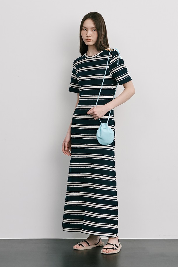 네이비 컬러의 스트라이프 자카드 니트 원피스입니다. 부드러운 Cotton 100% 소재로 제작되었으며, 봄, 여름 시즌에 어울리는 얇은 두께감과 A라인 핏, 라운드넥 디자인이 특징입니다. 허리를 잘록하게 잡아주는 실루엣과 밑단으로 갈수록 퍼지는 스커트 라인, 옆 네크 라인의 로고 금속 단추 디테일로 미니멀하면서도 클래식한 무드를 연출합니다.
