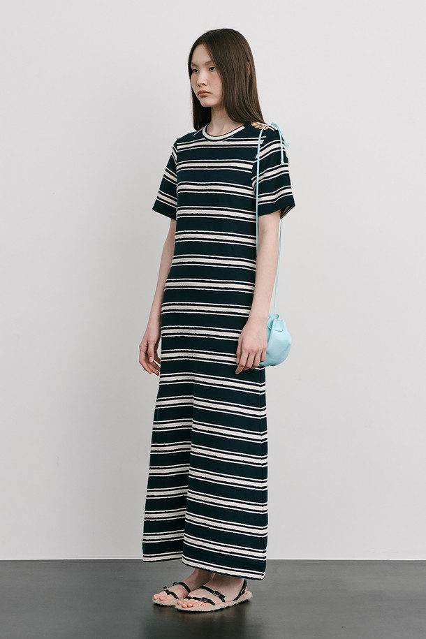 네이비 컬러의 스트라이프 자카드 니트 원피스입니다. 부드러운 Cotton 100% 소재로 제작되었으며, 봄, 여름 시즌에 어울리는 얇은 두께감과 A라인 핏, 라운드넥 디자인이 특징입니다. 허리를 잘록하게 잡아주는 실루엣과 밑단으로 갈수록 퍼지는 스커트 라인, 옆 네크 라인의 로고 금속 단추 디테일로 미니멀하면서도 클래식한 무드를 연출합니다.
