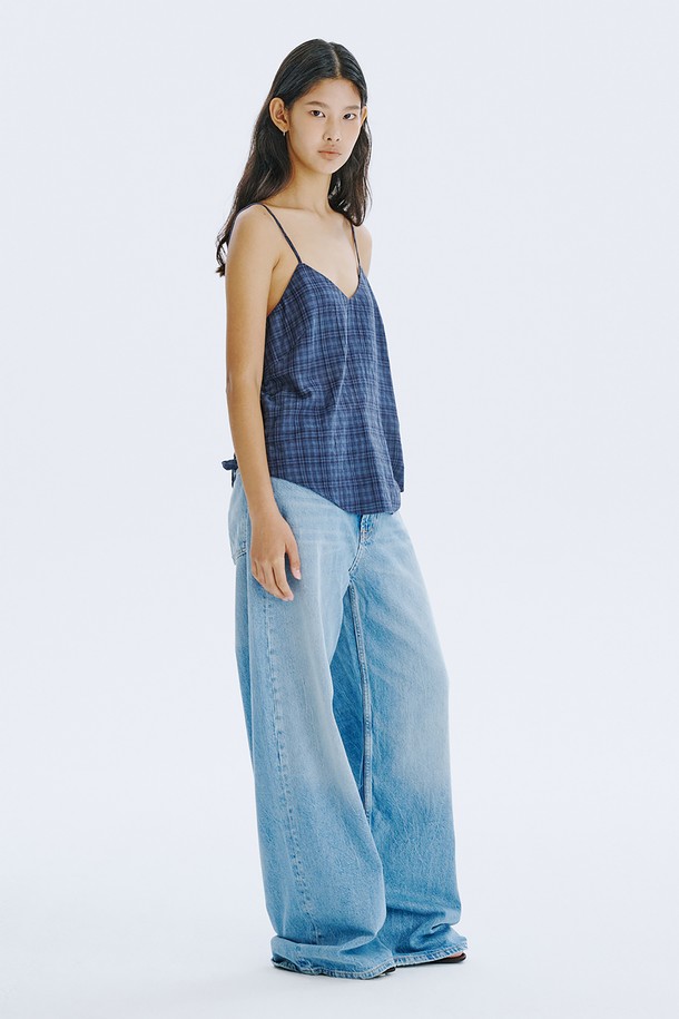 네이비 컬러의 체크 패턴이 돋보이는 민소매 탑입니다. 부드러운 면 80%와 레이온 20% 혼방 소재로 제작되어 시원하고 편안한 착용감을 선사하며, 브이넥 디자인에 아일렛 디테일과 끈 조절이 가능한 특징이 있습니다. 여름철 일상룩에 클래식하면서도 미니멀한 포인트를 더해줄 레귤러핏 상의입니다.
