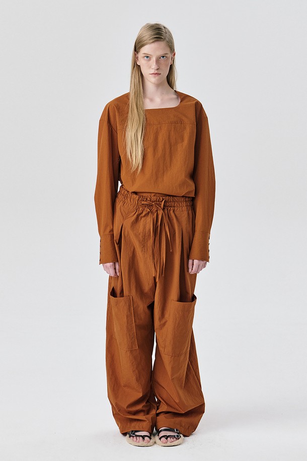 Yoke Top_브릭은 여성스러운 무드를 연출하는 블라우스입니다. 얇은 두께감의 나일론 소재로 제작되어 가을과 겨울에 적합하며 드라이한 촉감으로 편안한 착용감을 선사합니다. 톤 다운된 브릭 컬러와 미니멀, 모던, 아방가르드 스타일을 넘나드는 디자인이 특징입니다. 요크 절개 디테일과 구조적인 실루엣, 은은한 광택감이 돋보이며, 루즈핏으로 편안하게 착용 가능합니다. 출근룩, 오피스룩, 모임룩 등 다양한 TPO에 활용 가능하며 셋업 스타일로 시크하고 세련된 스타일링을 완성해보세요.
