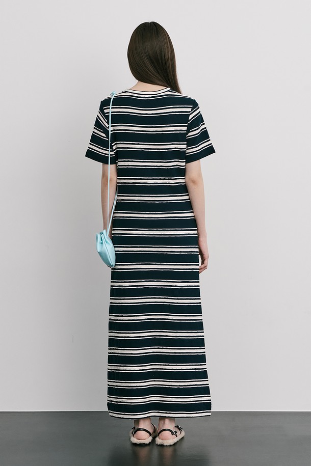 네이비 컬러의 스트라이프 자카드 니트 원피스입니다. 부드러운 Cotton 100% 소재로 제작되었으며, 봄, 여름 시즌에 어울리는 얇은 두께감과 A라인 핏, 라운드넥 디자인이 특징입니다. 허리를 잘록하게 잡아주는 실루엣과 밑단으로 갈수록 퍼지는 스커트 라인, 옆 네크 라인의 로고 금속 단추 디테일로 미니멀하면서도 클래식한 무드를 연출합니다.
