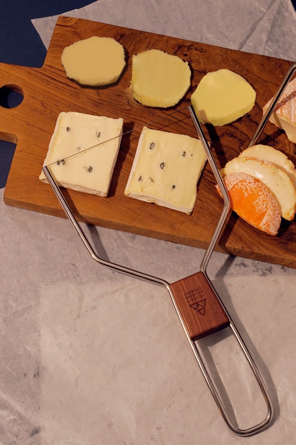 [트라이앵글] 와이어 치즈 슬라이서 13cm는 부드러운 치즈와 버터를 원하는 두께로 슬라이스할 수 있는 주방용품입니다. 식품 안전 소재인 스테인리스 스틸과 자두나무로 제작되었으며, 전체 길이 25.5cm, 너비 13cm의 사이즈입니다. 와이어 교체 및 장력 조절이 가능하며, 특허 디자인의 와이어 커팅 메커니즘과 목재 손잡이로 편리하게 사용할 수 있습니다. FSC 인증 목재를 사용하여 지속가능한 디자인을 구현하고, 교체용 와이어를 별도로 구매할 수 있습니다. 목재 손잡이의 자연스러운 무늬와 색상 차이는 제품의 특징을 더합니다.
