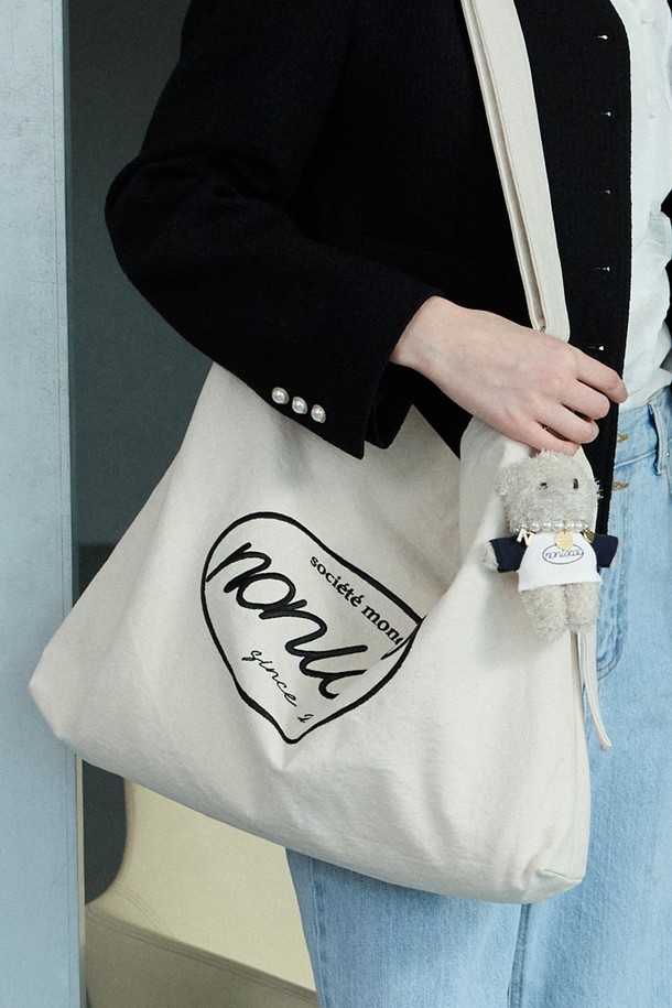 크림 색상의 로고 자수 에코백으로, 넉넉한 수납공간과 조절 가능한 스트랩이 있어 숄더 및 크로스백으로 활용 가능합니다. 면 소재로 제작되었으며, 입체적인 자수 디테일과 키 참 장식 가능한 디자인이 특징입니다. FREE 사이즈의 사각 라지 백으로, 실용적인 디자인이 돋보입니다.
