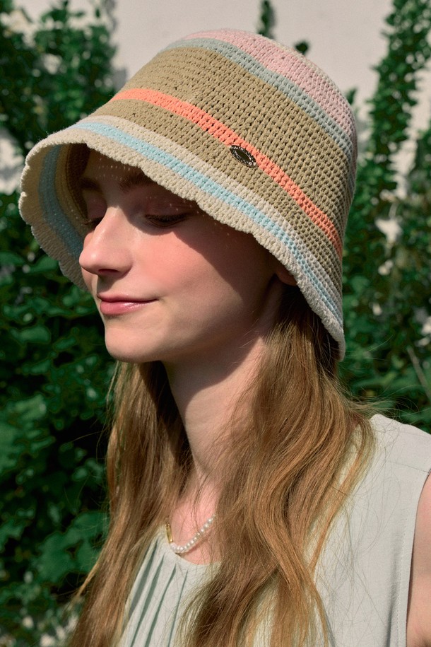 베이지 멀티와 아이보리 멀티 컬러의 Ripple Point Multi Stripe 버킷햇입니다. 여름 시즌에 어울리는 얇은 두께의 폴리에스테르 소재로 제작되어 가볍고 부드러운 촉감을 선사합니다. 페미닌하고 키치한 스타일을 연출하며, 웨이브 햄라인 디테일과 메탈 라벨 포인트가 돋보이는 디자인입니다.
