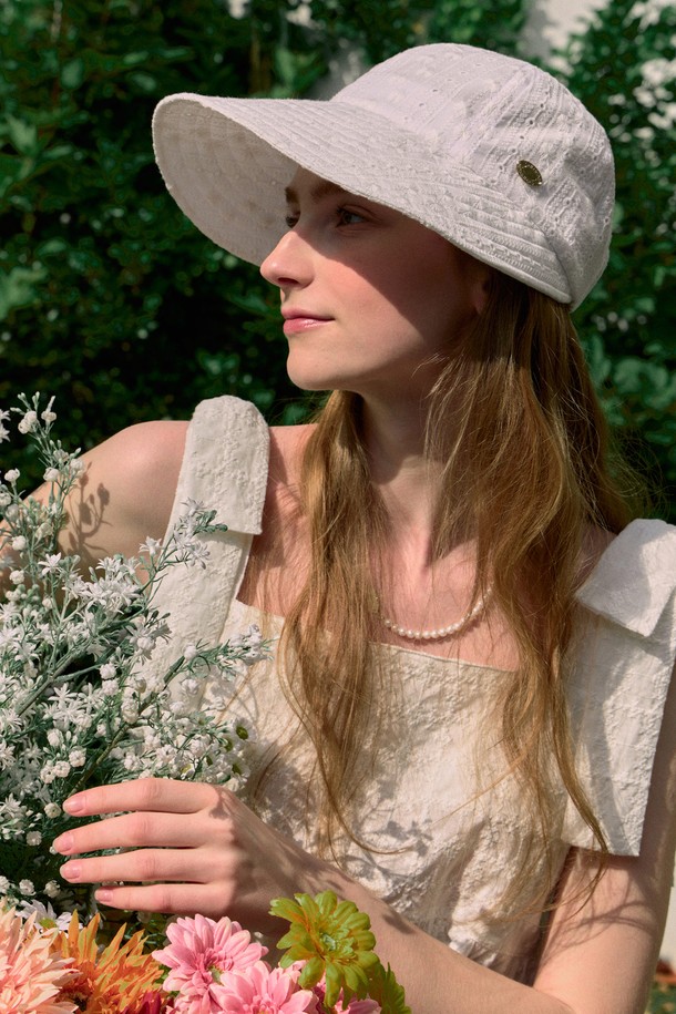 Amy 레이스 선바이저 - 화이트는 면 소재로 제작되어 부드러운 촉감과 뛰어난 통기성을 자랑하며, 봄, 여름철 햇볕으로부터 당신의 피부를 보호해줍니다. 챙 넓이 30.5cm, 모자 깊이 17cm의 이상적인 사이즈에 섬세한 레이스 패턴이 더해져 여성스러운 분위기를 연출하며, 벨크로 스트랩으로 간편하게 사이즈 조절이 가능합니다. 일상과 여행 어디에서나 스타일리시하게 연출할 수 있는 필수 아이템으로, 메탈 라벨 디테일이 고급스러움을 더합니다.
