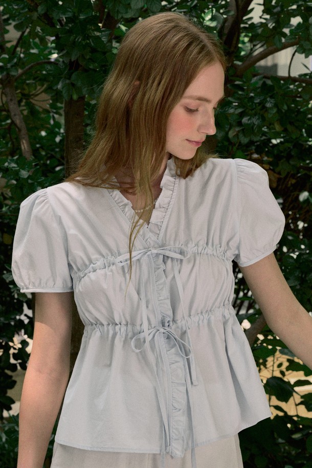 로맨틱한 무드의 라이트 블루 컬러 블라우스입니다. 면 소재로 제작되어 부드러운 촉감을 선사하며, 얇은 두께감으로 봄, 여름 시즌에 시원하게 착용하기 좋습니다. 셔링, 리본, 퍼프 소매, 러플 디테일이 여성스러운 분위기를 연출하며, 라운드 넥과 루즈핏으로 편안하게 즐겨 입을 수 있습니다.
