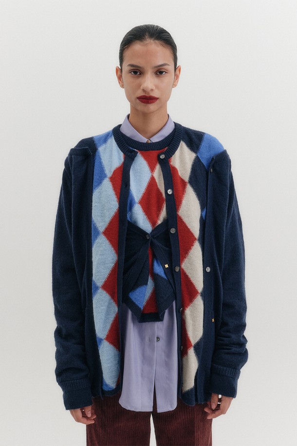 네이비 컬러의 아가일 패턴이 돋보이는 여성용 멀티 웨이 가디건입니다. 가을, 겨울 시즌에 어울리는 두꺼운 두께감으로 따뜻하게 착용할 수 있으며, 부드러운 촉감과 라운드넥 디자인이 특징입니다. 울, 알파카, 모헤어, 메리노울 등 다양한 고급 소재를 혼방하여 제작되었으며, 사이드 버튼 디테일과 멀티 웨이 스타일링이 가능하여 다양한 룩을 연출할 수 있습니다. 클래식하고 미니멀한 스타일을 즐기는 여성분들께 데이트룩, 모임룩, 출근룩 등 TPO에 맞춰 활용하기 좋은 아이템입니다. 레귤러 핏으로 편안하게 착용 가능하며, 긴 소매 기장으로 따뜻함과 스타일을 동시에 잡았습니다.
