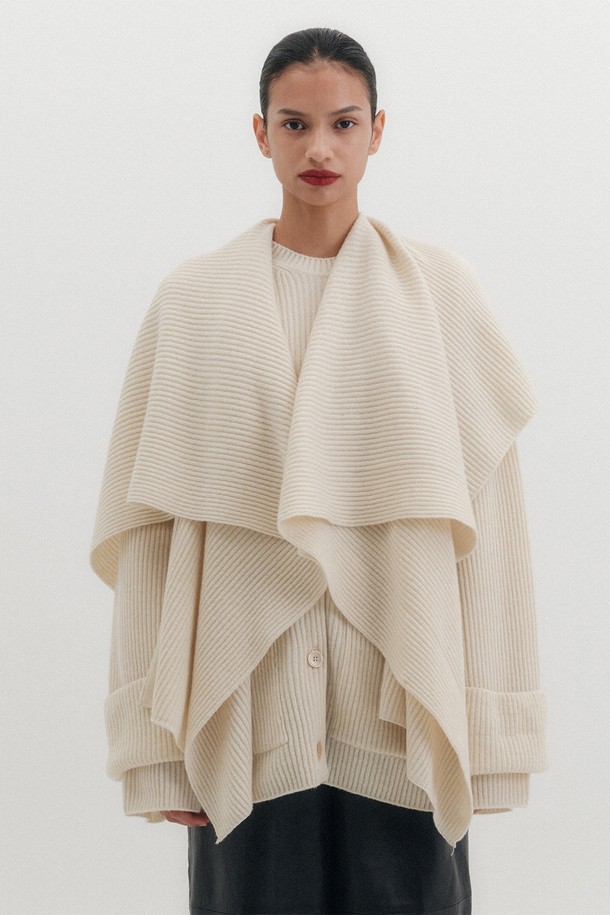 따뜻하고 포근한 분위기를 연출하는 멀티 웨이 숄 가디건 - 아이보리입니다. 부드러운 울 소재에 골지 패턴으로 고급스러운 질감을 더했으며, 숄 카라와 브이넥 디자인으로 다양한 스타일을 연출할 수 있습니다. 분리형 숄 머플러와 와이드 핏 슬리브, 패치 포켓 디테일이 특징이며, 루즈핏으로 편안한 착용감을 선사합니다. 가을, 겨울 시즌 데이트룩, 모임룩, 출근룩 등 클래식하고 미니멀한 스타일을 완성해보세요.
