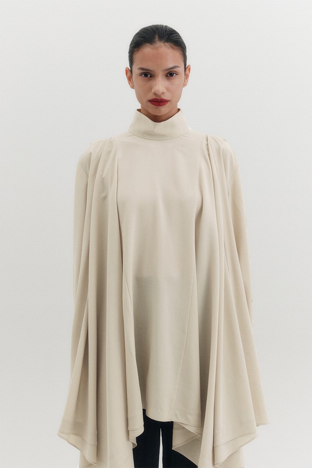 우아하고 세련된 무드를 선사하는 하이넥 플로우 블라우스입니다. 아이보리 컬러의 부드러운 레이온과 폴리에스테르 혼방 소재로 제작되어 편안한 착용감을 느낄 수 있습니다. 얇은 두께감과 루즈핏 디자인으로 자연스러운 실루엣을 연출하며, 언밸런스 헴라인과 플레어 디테일이 여성스러운 포인트를 더합니다. 긴소매와 하이넥 디자인은 클래식하면서도 세련된 스타일을 완성하며, 골드 로즈 버튼과 뒷면 버튼 여밈으로 퀄리티를 높였습니다. 모임룩, 데이트룩, 오피스룩 등 다양한 TPO에 활용하여 엘레강스하고 우아한 스타일을 연출해보세요.
