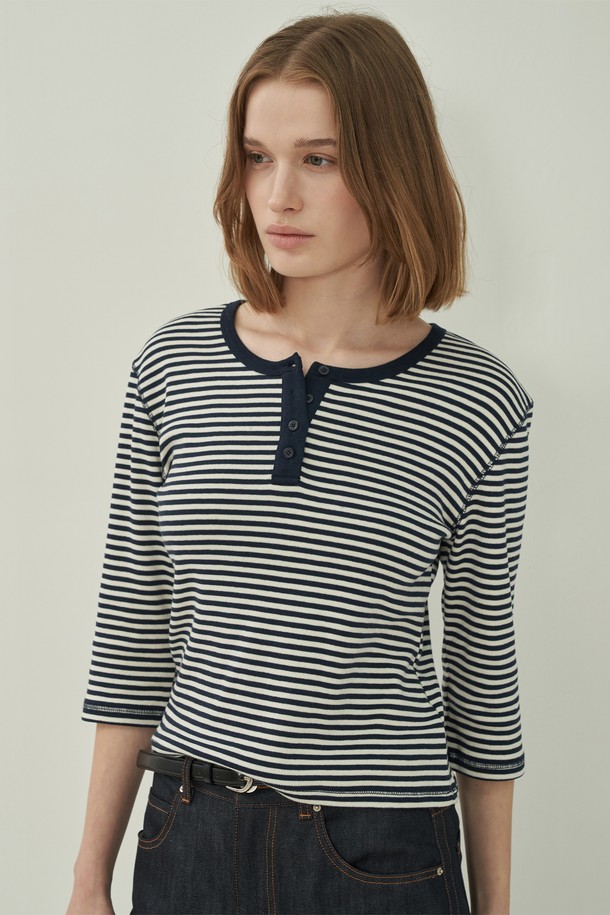 네이비와 화이트 스트라이프 패턴이 시원한 헨리넥 슬림 티셔츠입니다. 부드러운 면 소재로 제작되어 편안한 착용감을 선사하며, 봄, 여름 시즌 데이트룩이나 산책룩에 잘 어울립니다. 슬림핏 디자인으로 여성스러운 실루엣을 강조하며, 얇은 두께감과 반소매 기장으로 시원하게 입을 수 있습니다. 헨리넥 라인과 리본 디테일이 캐주얼하면서도 미니멀한 스타일을 완성하며, 다양한 하의와 매치하여 클래식한 무드를 연출할 수 있습니다.

