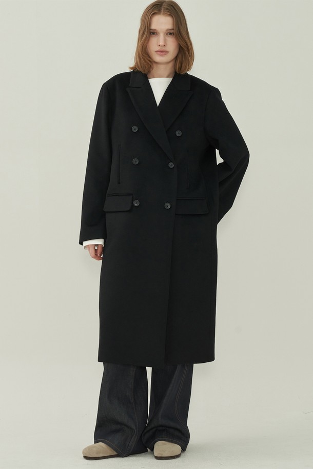 **울 더블 롱 코트 - Black**

세련된 여성의 겨울 스타일을 완성할 울 더블 롱 코트입니다. 미니멀하고 클래식한 디자인으로 오피스룩, 출근룩, 모임룩 등 다양한 TPO에 활용 가능합니다. 블랙 컬러의 무지 디자인과 오버핏, 롱 기장, 테일러드 칼라, 그리고 더블 버튼 여밈 방식이 특징입니다. 두꺼운 울 소재로 제작되어 한겨울에도 따뜻하게 착용할 수 있으며, 포켓 디테일로 실용성을 더했습니다.
