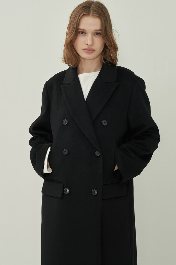 **울 더블 롱 코트 - Black**

세련된 여성의 겨울 스타일을 완성할 울 더블 롱 코트입니다. 미니멀하고 클래식한 디자인으로 오피스룩, 출근룩, 모임룩 등 다양한 TPO에 활용 가능합니다. 블랙 컬러의 무지 디자인과 오버핏, 롱 기장, 테일러드 칼라, 그리고 더블 버튼 여밈 방식이 특징입니다. 두꺼운 울 소재로 제작되어 한겨울에도 따뜻하게 착용할 수 있으며, 포켓 디테일로 실용성을 더했습니다.
