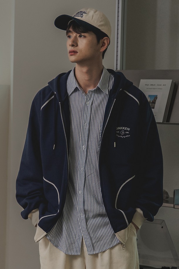 바켄 Essential 후드 집업 BK7988_네이비는 남녀 공용으로 착용 가능한 캐주얼 후드 집업입니다. 부드러운 촉감의 면, 폴리에스테르 혼방 두꺼운 프렌치테리 원단으로 제작되었으며, 오버핏 또는 릴랙스핏으로 편안하게 착용할 수 있습니다. 무지 디자인에 플랫락 스티치 공법, 자수 디자인, 대비색 디테일이 더해졌으며, 봄, 가을, 겨울에 활용하기 좋은 긴소매 집업 스타일입니다.
