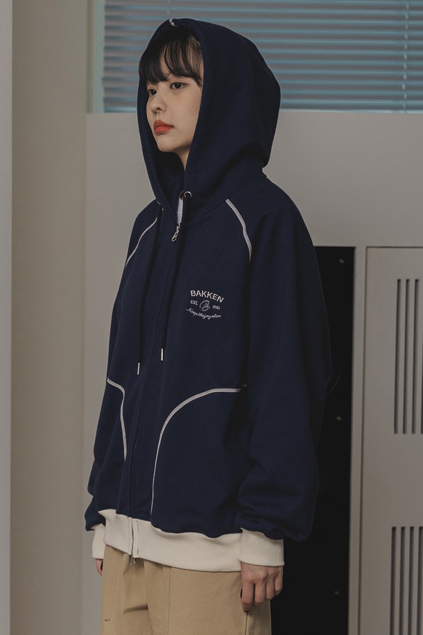 바켄 Essential 후드 집업 BK7988_네이비는 남녀 공용으로 착용 가능한 캐주얼 후드 집업입니다. 부드러운 촉감의 면, 폴리에스테르 혼방 두꺼운 프렌치테리 원단으로 제작되었으며, 오버핏 또는 릴랙스핏으로 편안하게 착용할 수 있습니다. 무지 디자인에 플랫락 스티치 공법, 자수 디자인, 대비색 디테일이 더해졌으며, 봄, 가을, 겨울에 활용하기 좋은 긴소매 집업 스타일입니다.
