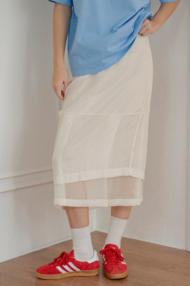 [25SS] P3226 시스루 밴딩 스커트는 여성스러운 분위기를 연출하는 시스루 스커트입니다. 부드러운 폴리에스테르 소재로 제작되어 은은한 비침과 플로잉 실루엣을 자랑하며, 얇은 두께감으로 봄, 여름 계절에 시원하게 착용하기 좋습니다. A라인 핏에 이중 레이어 디자인과 신축성 있는 이너 라이닝, 양쪽 슬릿 디테일이 더해져 우아하고 페미닌한 무드를 선사합니다. 블랙, 크림 두 가지 컬러로 출시되어 데이트룩, 카페룩, 모임룩 등 다양한 TPO에 맞춰 클래식, 미니멀, 로맨틱 스타일을 연출할 수 있습니다. 
