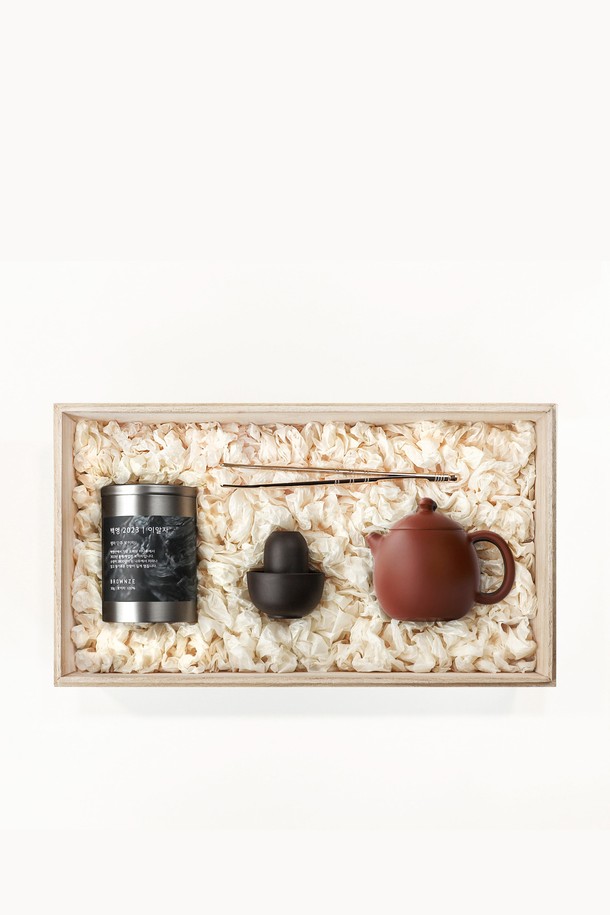 [브라운즈] 자사호 용단호 이알자 생차 선물세트는 다도에 필요한 용단호, 문향배 차잔세트, 브라스 차 집게, 백행 2023 이일자 생차로 구성되었습니다. 용단호는 복합 점토, 카올린, 운모, 석영, 산화철로 만들어졌으며, 유약을 바르지 않은 다공성 구조와 용의 알을 모티브로 한 전통적인 디자인이 특징입니다. 자니(갈색) 또는 흥니(적색) 색상으로 제공되며, 각각 1180°C, 1100°C에서 구워져 12%, 14%의 수축률을 보입니다.
