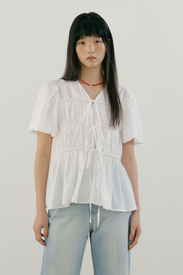 엘라 스트링 블라우스 (화이트)는 여성스러운 무드를 연출하는 여름용 블라우스입니다. 부드러운 레이온과 면 혼방 소재로 제작되어 얇고 가벼운 착용감을 선사하며, 루즈핏 디자인으로 편안함을 더합니다. 브이넥 라인과 반소매 기장으로 시원함을 강조하고, 리본 디테일과 앞중심 히든 후크 디테일이 여성스러움을 더합니다. 데이트룩, 카페룩, 모임룩 등 다양한 TPO에 어울리며, 미니멀, 클래식, 로맨틱 스타일을 즐기는 분들께 추천합니다. 레이어드하여 다양한 스타일을 연출할 수 있습니다.
