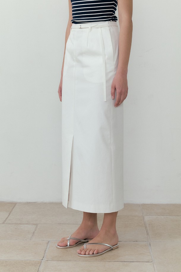 아이보리 컬러의 슬릿 포인트 벨티드 롱스커트입니다. 면과 폴리에스테르 혼방 소재로 제작되어 부드러운 촉감과 가벼운 착용감을 선사하며, H라인 핏과 레귤러핏으로 편안하게 착용할 수 있습니다. 허리 벨트와 D링 장식, 앞트임, 싱글 플리츠 디테일이 더해져 페미닌하면서도 캐주얼한 무드를 연출하며 여름철 일상복으로 활용하기 좋습니다.
