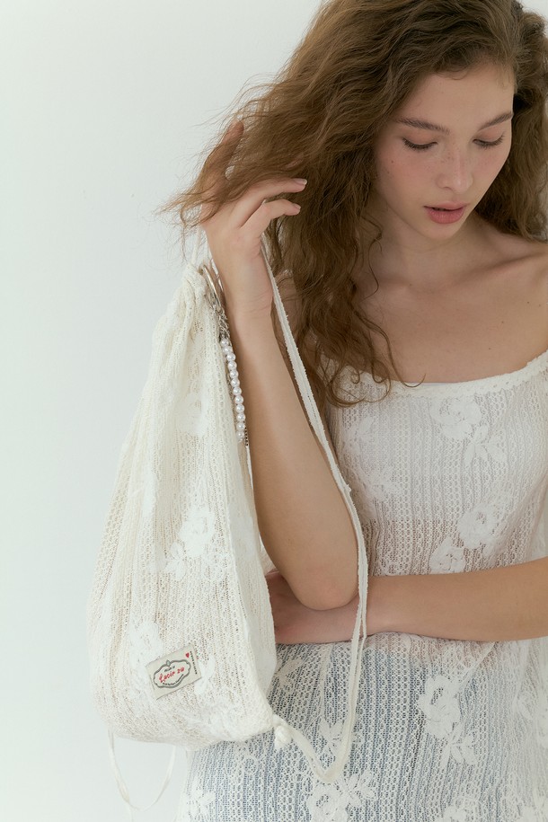 아이보리 컬러의 Wildflower 레이스 스트링 백팩입니다. 폴리에스터 소재의 미디엄 사이즈 사각 백팩으로, 레이스 플라워 패턴과 레이스 디자인 장식이 특징입니다. 36cm x 38cm 크기이며, 투웨이 스트랩과 빈티지 스타일을 더해 캐주얼하면서도 페미닌한 무드로 연출 가능하며, 조임용 끈으로 간편하게 잠글 수 있습니다. (사이즈는 1-3cm 오차가 있을 수 있습니다.)
