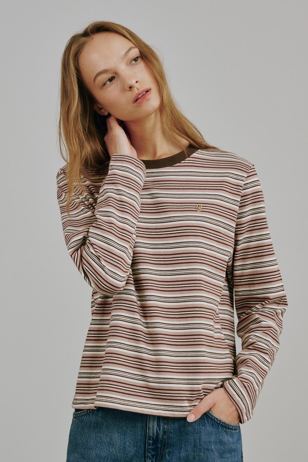 베이지 컬러의 스트라이프 롱 슬리브 티셔츠입니다. 면과 폴리에스테르 혼방 소재로 제작되어 부드러운 촉감과 중간 두께로 봄, 가을에 착용하기 좋습니다. 라운드넥에 레귤러핏으로 편안하게 연출 가능하며, 캐주얼, 미니멀, 클래식 스타일을 모두 소화합니다. 메탈 로고 디테일이 돋보이며, 모던한 실루엣과 프리미엄 소재감이 특징입니다. 카페룩이나 동네 마실룩에 잘 어울리는 아이템입니다.
