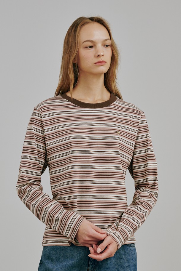 베이지 컬러의 스트라이프 롱 슬리브 티셔츠입니다. 면과 폴리에스테르 혼방 소재로 제작되어 부드러운 촉감과 중간 두께로 봄, 가을에 착용하기 좋습니다. 라운드넥에 레귤러핏으로 편안하게 연출 가능하며, 캐주얼, 미니멀, 클래식 스타일을 모두 소화합니다. 메탈 로고 디테일이 돋보이며, 모던한 실루엣과 프리미엄 소재감이 특징입니다. 카페룩이나 동네 마실룩에 잘 어울리는 아이템입니다.
