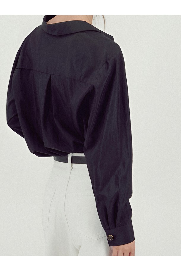 [25FW] 글로시 셔츠 블라우스 _블랙은 미니멀하고 클래식한 스타일을 추구하는 여성들을 위한 셔츠/블라우스입니다. 부드러운 촉감의 레이온과 나일론 혼방 소재로 제작되었으며, 사계절 내내 착용 가능합니다. 블랙 컬러, 루즈핏, 얇은 두께로 편안한 착용감을 선사하며 오피스룩, 출근룩, 모임룩 등 다양한 TPO에 활용하기 좋습니다. 미니 칼라 디자인과 메탈 로고 프린트 칼라, 로고 버튼 디테일, 소매 개더링, 광택감 있는 소재가 특징입니다. 긴 소매 기장으로 시크한 무드를 연출합니다.
