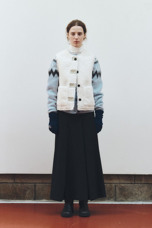 아이보리 컬러의 리버시블 셔링 베스트입니다. 양털과 쉬어링 소재로 제작되어 부드러운 촉감과 두꺼운 두께감으로 따뜻하게 착용할 수 있습니다. 가을, 겨울 시즌에 어울리는 레귤러 핏의 민소매 베스트로, 버튼 여밈 방식과 무지 디자인이 클래식하고 미니멀한 스타일을 연출합니다. 양면 착용이 가능하여 다양한 스타일로 활용할 수 있는 실용적인 아우터입니다. 데일리룩을 완성하는 데 적합한 아이템입니다.
