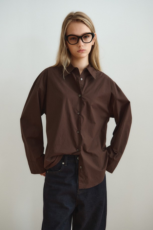 RELAXED COTTON SHIRT_DARK BROWN (릴랙스드 코튼 셔츠_다크 브라운)은 미니멀하고 베이직한 스타일의 여성 셔츠/블라우스입니다. 다크 브라운 컬러의 무지 디자인으로, 사계절 내내 활용 가능하며 출근룩과 모임룩에 적합합니다. 부드러운 촉감의 면 소재로 제작되었으며, 릴랙스핏과 루즈핏으로 편안한 착용감을 제공합니다. 얇은 두께의 레귤러 기장 셔츠로, 와이드 슬리브 디자인과 조절 가능한 소매 커프스가 특징이며, 레이어드하여 다양한 스타일을 연출할 수 있습니다. 차이나칼라와 긴 소매 디자인으로 미니멀, 클래식, 캐주얼 등 폭넓은 스타일을 소화할 수 있습니다.
