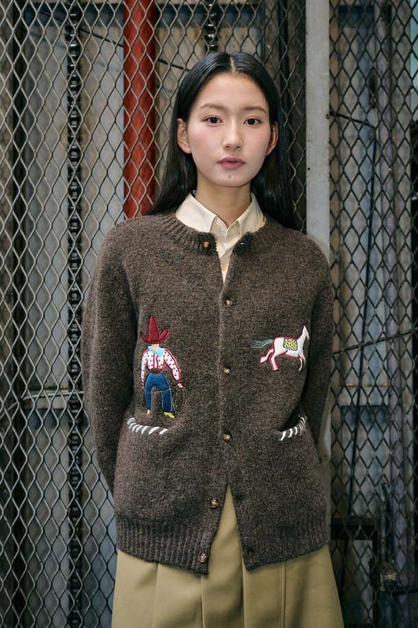 **[25FW] UNISEX 카우보이 크루넥 가디건 [4COL] / SBE4U04013**

이번 시즌, 캐주얼하고 클래식한 스타일을 연출할 수 있는 유니섹스 카우보이 크루넥 가디건입니다. 부드러운 울 소재로 제작되어 가을과 겨울에 따뜻하게 착용할 수 있으며, 두께감이 있어 포근한 착용감을 선사합니다. 크루넥 디자인과 레귤러 핏으로 편안하게 착용 가능하며, 카우보이 모티프 자수 패턴이 돋보이는 디자인입니다. 네이비, 브라운 두 가지 컬러로 출시되어 다양한 스타일 연출에 활용할 수 있습니다. 긴 소매 기장의 레귤러핏 가디건으로 데일리룩에 포인트 아이템으로 활용해보세요.
