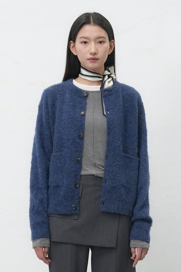 **[25FW] UNISEX 헤어리 니트 포켓 가디건**은 부드러운 울 소재로 제작되어 따뜻하고 포근한 착용감을 선사합니다. 가을과 겨울에 어울리는 두꺼운 두께감과 긴 소매 기장으로 보온성을 높였으며, 넉넉한 레귤러 핏으로 편안하게 착용할 수 있습니다. 캐주얼, 클래식, 미니멀 스타일을 모두 소화 가능하며, 무지 디자인과 네이비 컬러로 다양한 룩에 활용하기 좋습니다. 싱글 버튼 여밈과 포켓, 헤어리 텍스처 디테일이 돋보이며, 출근룩과 모임룩 등 TPO에 구애받지 않고 즐겨 입을 수 있습니다.
