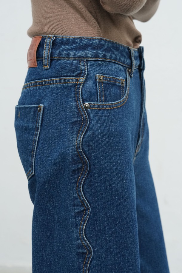 **[25FW] WOMAN 스캘럽 세미 와이드 데님 팬츠 [BLUE] / WBE4L11512**

세련된 여성 데이트룩과 출근룩을 완성해 줄 [25FW] WOMAN 스캘럽 세미 와이드 데님 팬츠입니다. 캐주얼, 미니멀, 클래식 스타일을 모두 아우르는 디자인으로, 가을과 겨울에 따뜻하게 착용할 수 있습니다. 블루 컬러의 무지 데님 소재로 제작되었으며, 넉넉한 루즈핏의 세미 와이드 핏이 편안함을 선사합니다. 밑단 스캘럽 디테일이 여성스러운 포인트를 더해줍니다. 데님 특유의 자연스러운 질감과 디자인이 돋보이는 아이템입니다.
