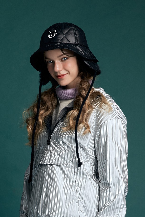 블랙 색상의 여성 패딩 버킷햇입니다. 보온성을 높여주는 두꺼운 두께의 패딩 소재와 부드러운 촉감이 특징입니다. 챙 넓이 6cm로 햇빛을 가려주며, 귀여운 캐릭터 자수와 퍼 장식이 디자인에 포인트를 더합니다. 골프룩, 캐주얼, 클래식 스타일 모두에 잘 어울리며, 이어워머 디테일과 턱끈, 사이즈 조절 기능으로 실용성을 높였습니다. 겨울철 따뜻하고 스타일리시하게 착용할 수 있는 아이템입니다.
