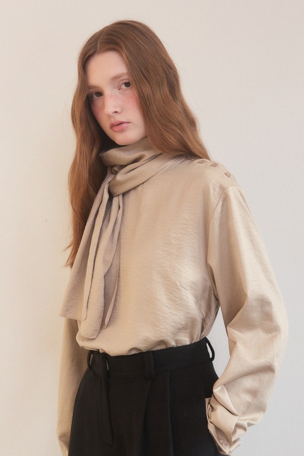 베이지 색상의 새틴 사이드 버튼 스카프 넥 블라우스는 우아하고 엘레강스한 스타일을 연출합니다. 릴랙스핏으로 편안함을 더했으며, 폴리에스테르와 나일론 혼방 소재로 부드러운 촉감을 선사합니다. 긴 소매와 중간 두께감으로 겨울철에도 따뜻하게 착용할 수 있으며, 오피스룩, 모임룩, 소개팅룩 등 다양한 TPO에 활용 가능합니다. 어깨 버튼 장식과 스카프 넥라인의 리본 디테일이 돋보이며, 오프숄더 스타일링도 가능하여 클래식, 미니멀, 로맨틱 무드를 모두 만족시키는 아이템입니다.
