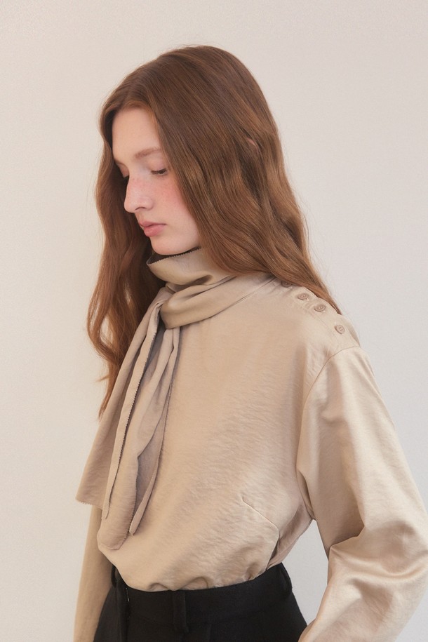 베이지 색상의 새틴 사이드 버튼 스카프 넥 블라우스는 우아하고 엘레강스한 스타일을 연출합니다. 릴랙스핏으로 편안함을 더했으며, 폴리에스테르와 나일론 혼방 소재로 부드러운 촉감을 선사합니다. 긴 소매와 중간 두께감으로 겨울철에도 따뜻하게 착용할 수 있으며, 오피스룩, 모임룩, 소개팅룩 등 다양한 TPO에 활용 가능합니다. 어깨 버튼 장식과 스카프 넥라인의 리본 디테일이 돋보이며, 오프숄더 스타일링도 가능하여 클래식, 미니멀, 로맨틱 무드를 모두 만족시키는 아이템입니다.
