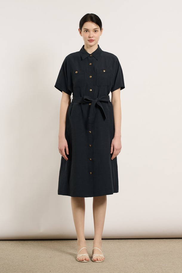 [25SU] 투포켓 린넨 벨티드 원피스 - DARK NAVY B5M4O62856은 린넨, 레이온, 폴리에스터 혼방 소재로 제작된 여성용 여름 원피스입니다. 다크 네이비 색상의 무지 패턴이며, 셔츠칼라와 반소매 디자인으로 클래식한 무드를 연출합니다. 두 개의 포켓과 벨트, 버튼 디테일이 돋보이며, 어깨와 소매 부분의 여유로운 디자인과 자연스럽게 흐르는 실루엣이 특징인 레귤러핏 원피스입니다.
