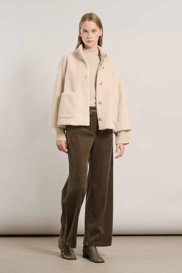 [25WT] 밴드넥 FAKE 무스탕 - IVORY A5WAF81513은 부드러운 촉감의 인조 가죽 소재로 제작된 여성용 무스탕입니다. 밴드넥 디자인과 크롭 기장으로 캐주얼하고 베이직한 스타일을 연출하며, 겨울철 따뜻하게 착용할 수 있습니다. 아이보리 컬러의 무지 디자인에 레귤러 핏으로 어떤 옷에도 쉽게 매치할 수 있습니다. 안감은 퍼 소재로 되어 있어 보온성을 높였으며, 긴 소매와 버튼 여밈 방식이 특징입니다.