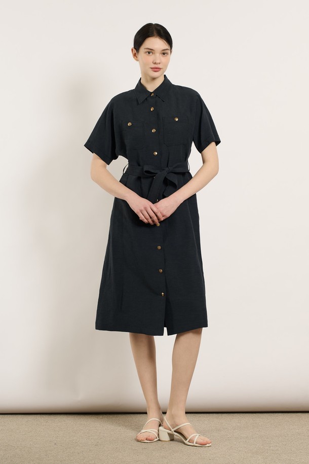 [25SU] 투포켓 린넨 벨티드 원피스 - DARK NAVY B5M4O62856은 린넨, 레이온, 폴리에스터 혼방 소재로 제작된 여성용 여름 원피스입니다. 다크 네이비 색상의 무지 패턴이며, 셔츠칼라와 반소매 디자인으로 클래식한 무드를 연출합니다. 두 개의 포켓과 벨트, 버튼 디테일이 돋보이며, 어깨와 소매 부분의 여유로운 디자인과 자연스럽게 흐르는 실루엣이 특징인 레귤러핏 원피스입니다.
