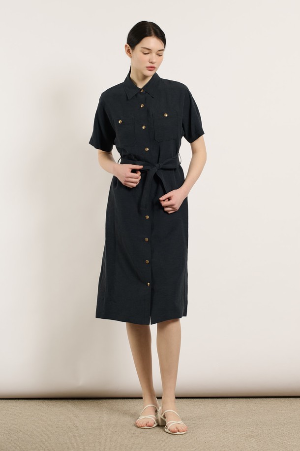 [25SU] 투포켓 린넨 벨티드 원피스 - DARK NAVY B5M4O62856은 린넨, 레이온, 폴리에스터 혼방 소재로 제작된 여성용 여름 원피스입니다. 다크 네이비 색상의 무지 패턴이며, 셔츠칼라와 반소매 디자인으로 클래식한 무드를 연출합니다. 두 개의 포켓과 벨트, 버튼 디테일이 돋보이며, 어깨와 소매 부분의 여유로운 디자인과 자연스럽게 흐르는 실루엣이 특징인 레귤러핏 원피스입니다.
