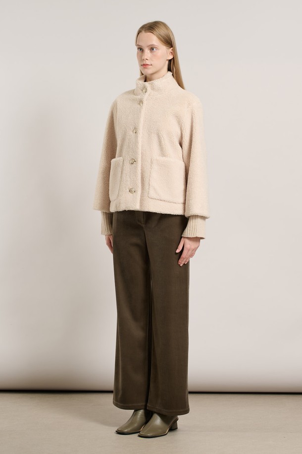 [25WT] 밴드넥 FAKE 무스탕 - IVORY A5WAF81513은 부드러운 촉감의 인조 가죽 소재로 제작된 여성용 무스탕입니다. 밴드넥 디자인과 크롭 기장으로 캐주얼하고 베이직한 스타일을 연출하며, 겨울철 따뜻하게 착용할 수 있습니다. 아이보리 컬러의 무지 디자인에 레귤러 핏으로 어떤 옷에도 쉽게 매치할 수 있습니다. 안감은 퍼 소재로 되어 있어 보온성을 높였으며, 긴 소매와 버튼 여밈 방식이 특징입니다.